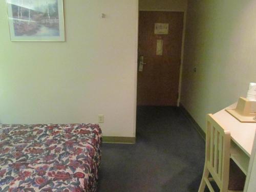 a room with a bed and a desk and a door at Microtel Inn by Wyndham Champaign in Champaign