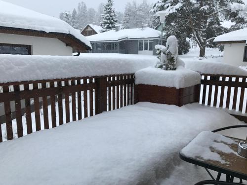 a yard covered in snow next to a fence at Apartmány Pinie Lipno in Lipno nad Vltavou