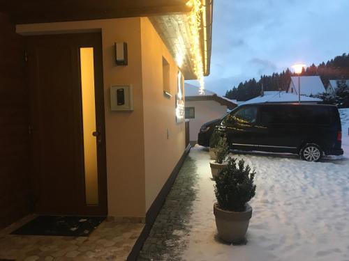 a van parked outside of a house with snow on the ground at Apartmány Pinie Lipno in Lipno nad Vltavou