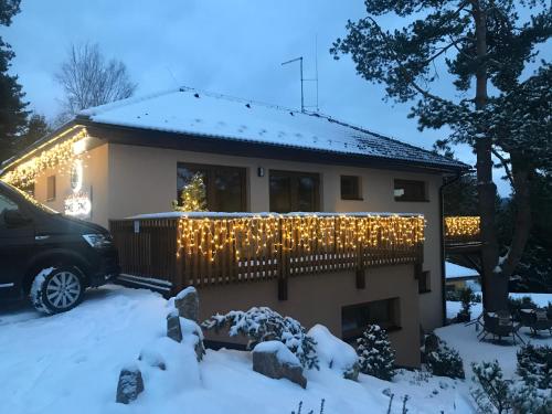 a house covered in christmas lights in the snow at Apartmány Pinie Lipno in Lipno nad Vltavou