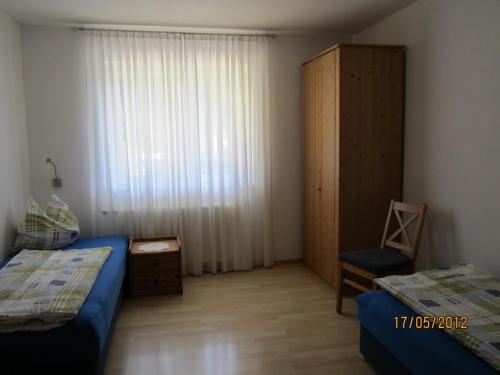a bedroom with two beds and a window and a chair at Landhaus Bürse in Flattach