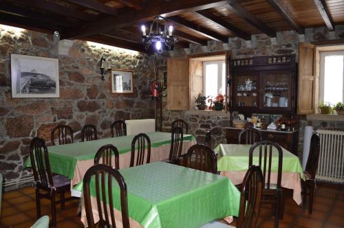 a dining room with tables and chairs and a stone wall at Casa Loureiro in Caldas de Reis