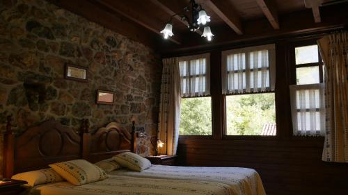 a bedroom with two beds and two windows at Hotel Rural Los Texos in La Riera