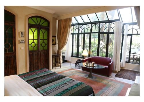 a bedroom with a bed and a table and windows at La Maison de Tanger in Tangier
