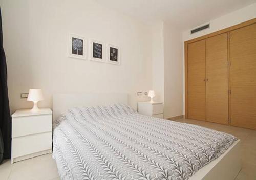 a white bedroom with a large bed and a wooden closet at Samara Marbella Apartment in Marbella
