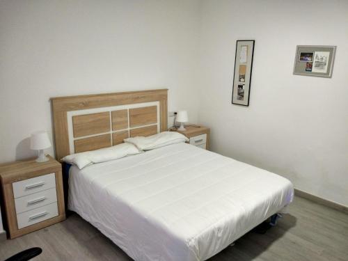 a bedroom with a large white bed and a night stand at Playa Precioso apartamento para familia con niños in San Juan de Alicante