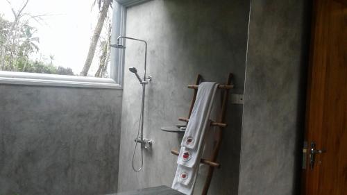 a bathroom with a shower with a towel hanging on the wall at Happy Man Village in Bentota