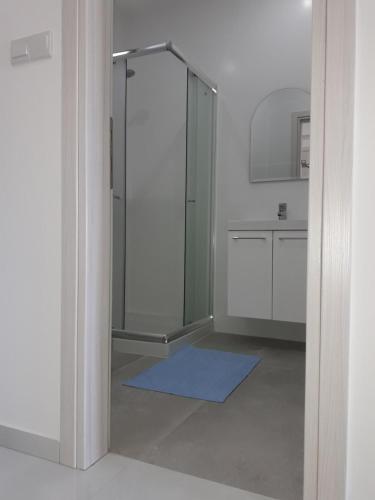 a bathroom with a glass shower and a blue rug at P.L Hermes Studios & Apartments in Larnaka