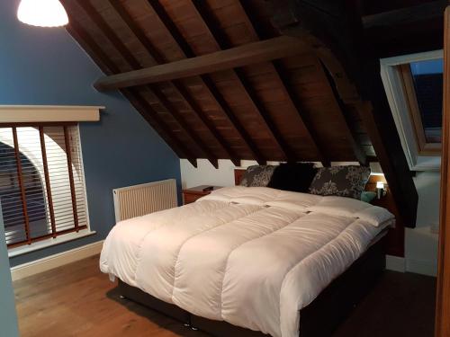 a large bed in a bedroom with a wooden ceiling at Renovated Church close to the beach in Llanelli