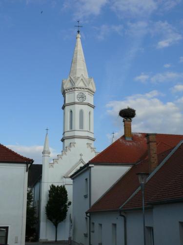 a white church with a tower with a clock on it at Pension Peterhof in Mörbisch am See