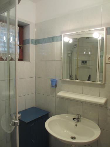a white bathroom with a sink and a mirror at Apartmani Sirovica in Čunski