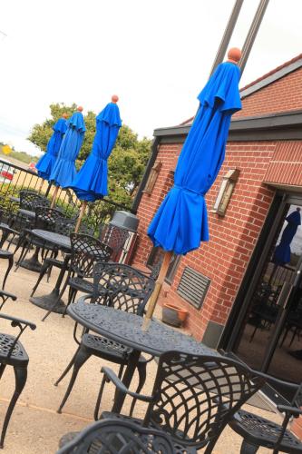 a row of tables and chairs with blue umbrellas at Plaza Inn Midland in Midland