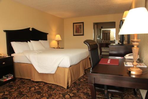 a hotel room with a bed and a desk with a desk at Plaza Inn Midland in Midland