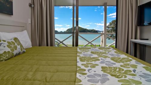 Schlafzimmer mit einem Bett und Blick auf das Wasser in der Unterkunft Breakwater Motel in Paihia