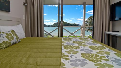 a bedroom with a bed with a view of the water at Breakwater Motel in Paihia