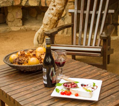 a table with a bottle of wine and a bowl of fruit at LittleBush Private Lodge in Hoedspruit