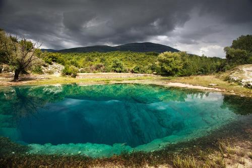 a large pool of blue water in a field at Apartment Lavanda in Sinj