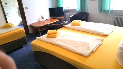 a room with two beds with yellow towels on them at Hotel Haus Frieling in Dortmund