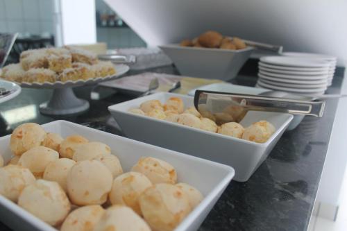 a buffet with plates and bowls of food on a counter at Pousada Orquideas de Maria in Aparecida