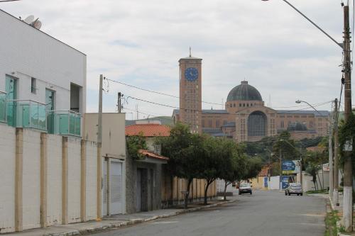 a building with a clock tower in the distance with a street at Pousada Orquideas de Maria in Aparecida