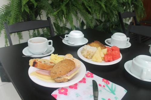 a table with two plates of food and cups of coffee at Pousada Orquideas de Maria in Aparecida