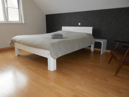 Cama blanca en habitación con suelo de madera en Chez Paul, en Ypres