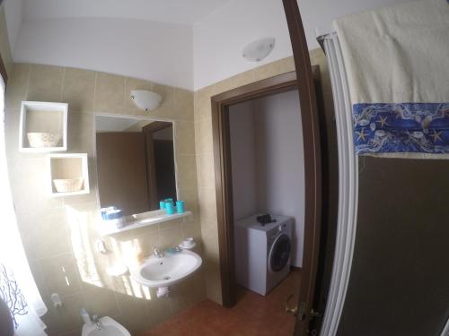 een badkamer met een wastafel, een toilet en een spiegel bij Appartamento a Vignola Mare in Aglientu
