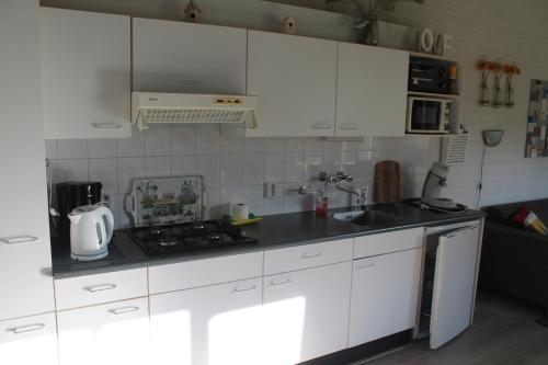 een keuken met witte kasten en een fornuis met oven bij Rustige, gelijkvloerse vakantiewoning met 2 slaapkamers in Simpelveld, Zuid-Limburg in Simpelveld