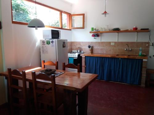 a kitchen with a wooden table and a refrigerator at El Portal del Lago in Lago Puelo