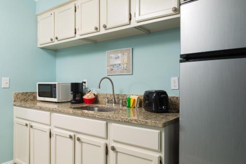 a kitchen with white cabinets and a sink and a refrigerator at The Saint Augustine Beach House in Saint Augustine