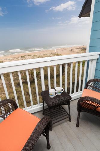 a balcony with two chairs and a table with two cups at The Saint Augustine Beach House in Saint Augustine