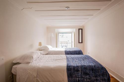 two beds in a white room with a window at Rua Sao Bento Apartment in Lisbon