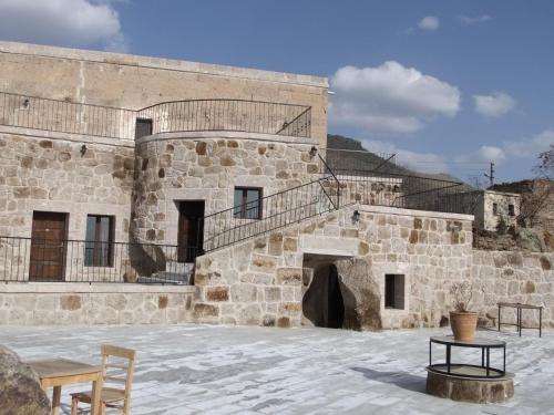 an old stone building with a staircase and a patio at Kapadokya Ihlara Konaklari & Caves in Guzelyurt