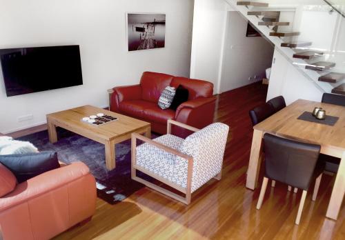 a living room with a red couch and a table at Sullivans Cove Apartments in Hobart