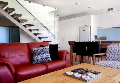 a living room with a red couch and a table at Sullivans Cove Apartments in Hobart