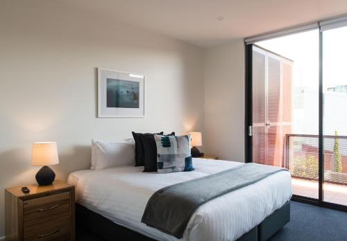 a bedroom with a bed and a large window at Sullivans Cove Apartments in Hobart