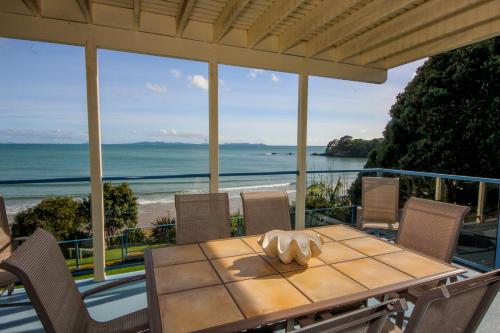 a table on a patio with a view of the ocean at By the Bay Beachfront Apartments in Mangonui