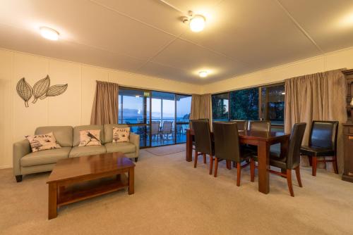a living room with a couch and a table and chairs at By the Bay Beachfront Apartments in Mangonui