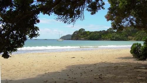 a view of a beach with a boat in the water at By the Bay Beachfront Apartments in Mangonui