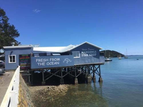 a restaurant on a dock on a body of water at By the Bay Beachfront Apartments in Mangonui