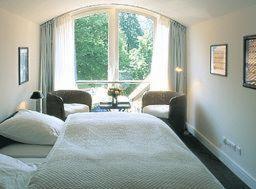 a bedroom with two beds and a large window at Hotel Village in Worpswede