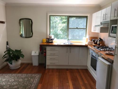 una cocina con armarios blancos y una ventana en Ghost Hill Road Retreat, en Bilpin