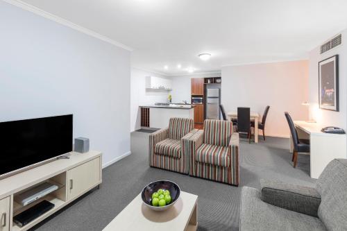 a living room with a couch and a tv at Oaks Brisbane Lexicon Suites in Brisbane