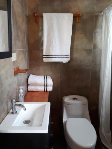 a bathroom with a sink and a toilet and towels at Posada Soleil Bed & Breakfast in Valle de Guadalupe