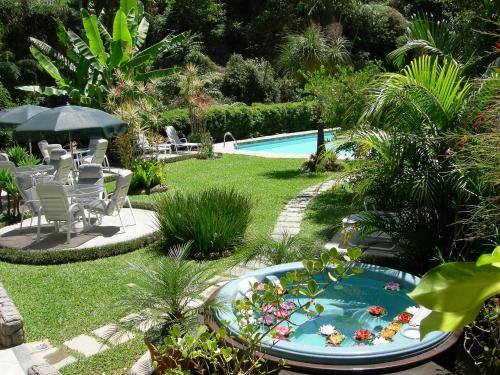 a garden with a pool and a table and chairs at Hotel Akaskay in Nova Friburgo