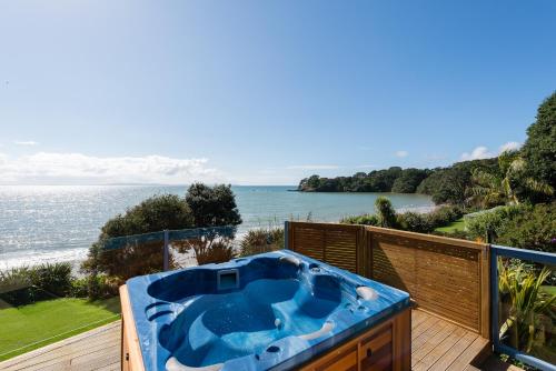 a hot tub on a deck next to the ocean at By the Bay Beachfront Apartments in Mangonui