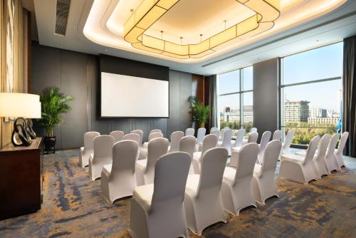 a conference room with white chairs and a screen at Shangri-La Jinan in Jinan