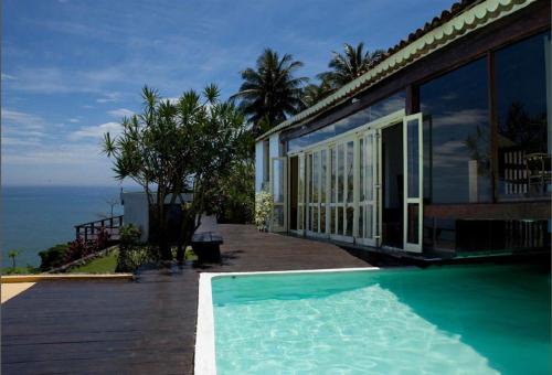 une maison avec une piscine à côté de l'océan dans l'établissement CLIFFSIDE - Boutique Hotel & Spa, à Rio de Janeiro