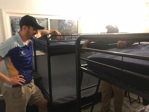 a man is standing next to two bunk beds at Tallahassee Sun & Moon in Tallahassee