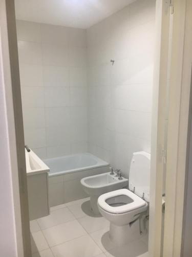 a white bathroom with a toilet and a bath tub at Departamento en Palermo Soho in Buenos Aires